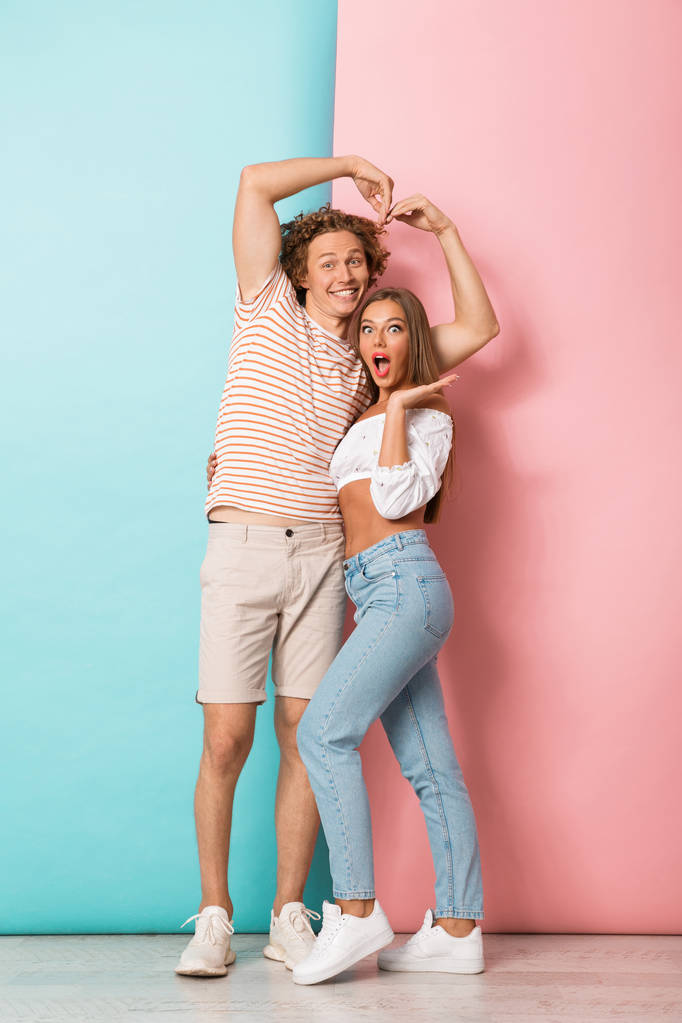 Ganzkörperporträt eines glücklichen jungen verliebten Paares auf zweifarbigem Hintergrund - Foto, Bild