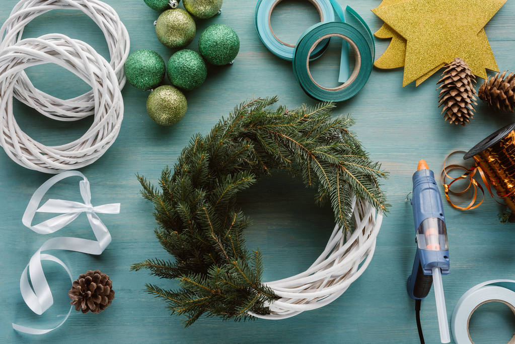 posa piatta con rami di pino disposti e decorazioni per ghirlanda di Natale fatta a mano su un tavolo di legno blu
 - Foto, immagini