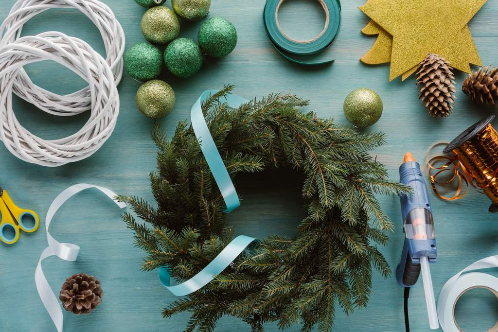 青い木製卓上に整理された松の木の枝と手作りクリスマス リース飾りのトップ ビュー - 写真・画像