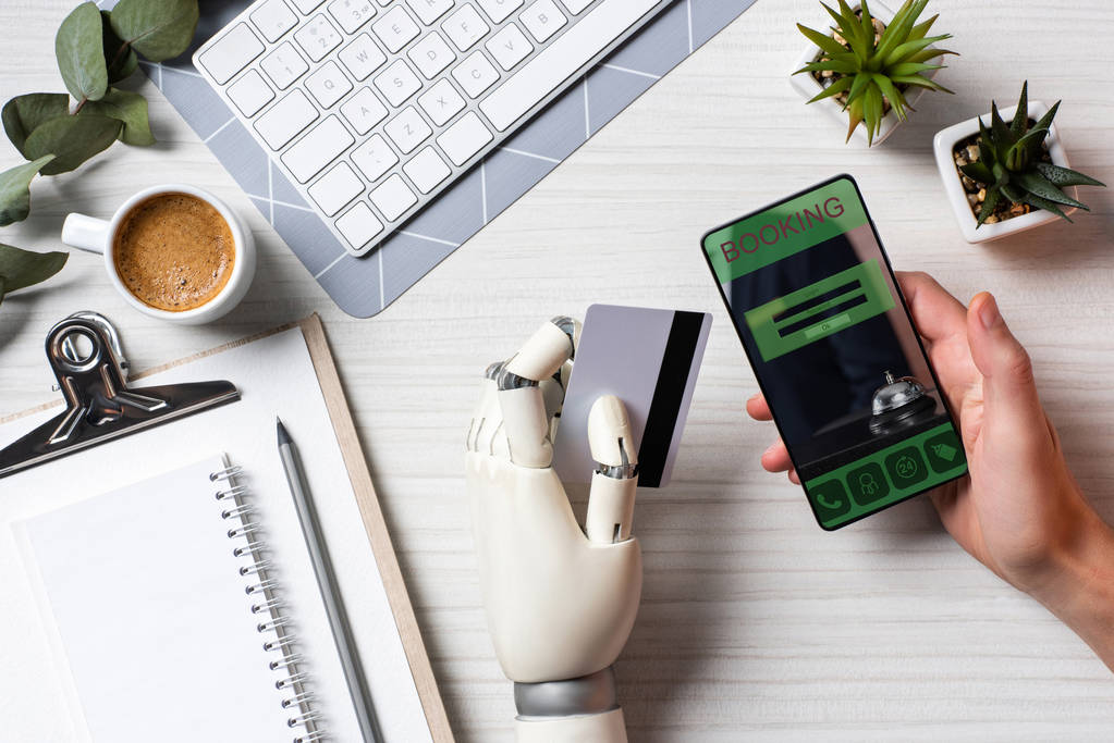 частковий вид на бізнесмена з протезом рука тримає кредитну картку і використовує смартфон з бронюванням на екрані за столом в офісі
  - Фото, зображення