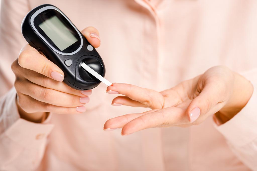 image recadrée de la femme mesurant le taux de glucose dans le sang avec glucomètre isolé sur blanc, concept de diabète
 - Photo, image