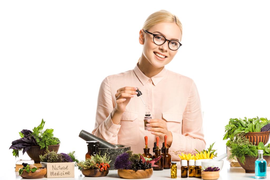 smiling woman in glasses making essential oil isolated on white and looking at camera - Photo, Image