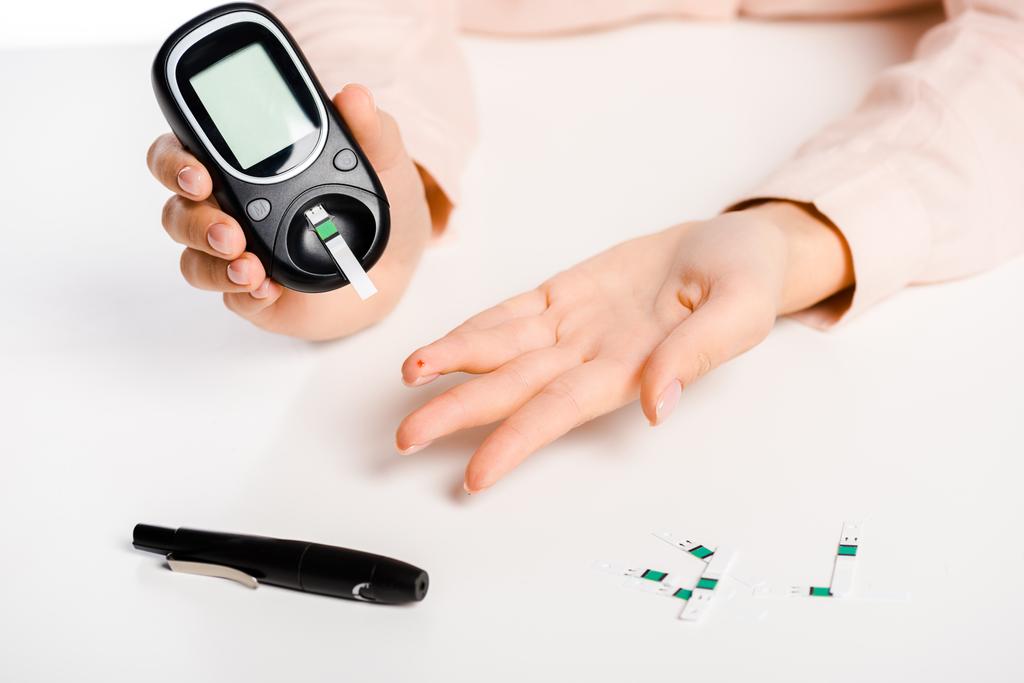 imagem cortada da mulher medindo nível de glicose no sangue com glicosímetro isolado em branco, conceito de diabetes
 - Foto, Imagem