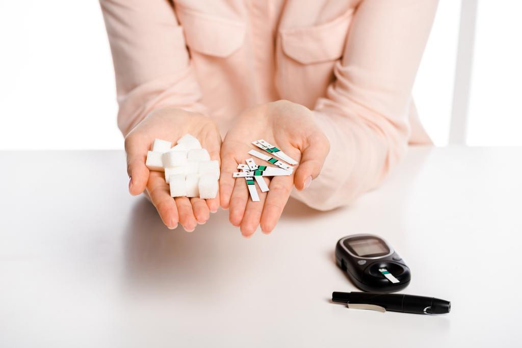 Şeker Ölçüm tutan kadın kırpılmış görüntü şeritler ve rafine şeker elinde beyaz, diyabet kavramı izole - Fotoğraf, Görsel