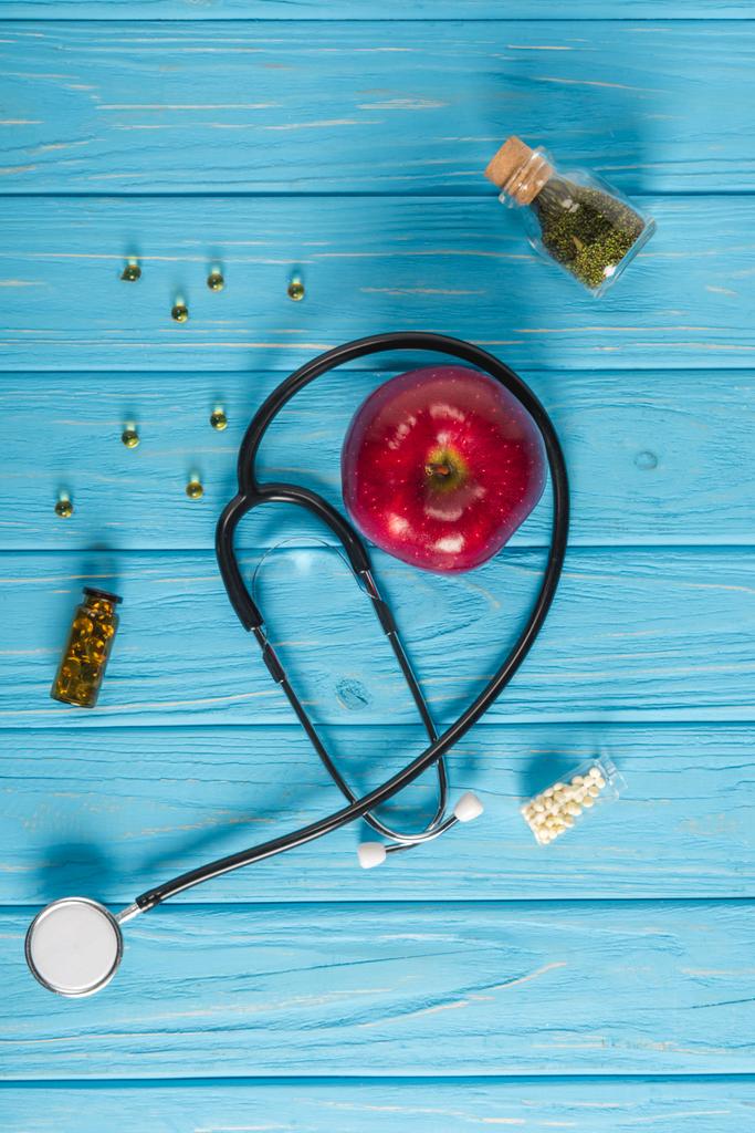 felülnézet, piros alma, sztetoszkóp és alternatív gyógyászat kábítószer fa türkiz asztallapra - Fotó, kép