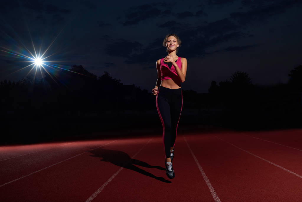 Positività donna che corre allenamento sullo stadio durante la notte
. - Foto, immagini