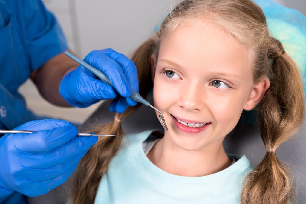 vágott lövés a fogorvos eszközökkel boldog kis gyermek fogak vizsgálata - Fotó, kép
