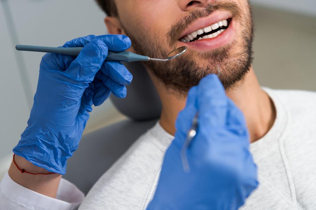 recortado tiro de mujer dentista examinar dientes de feliz cliente
 - Foto, Imagen