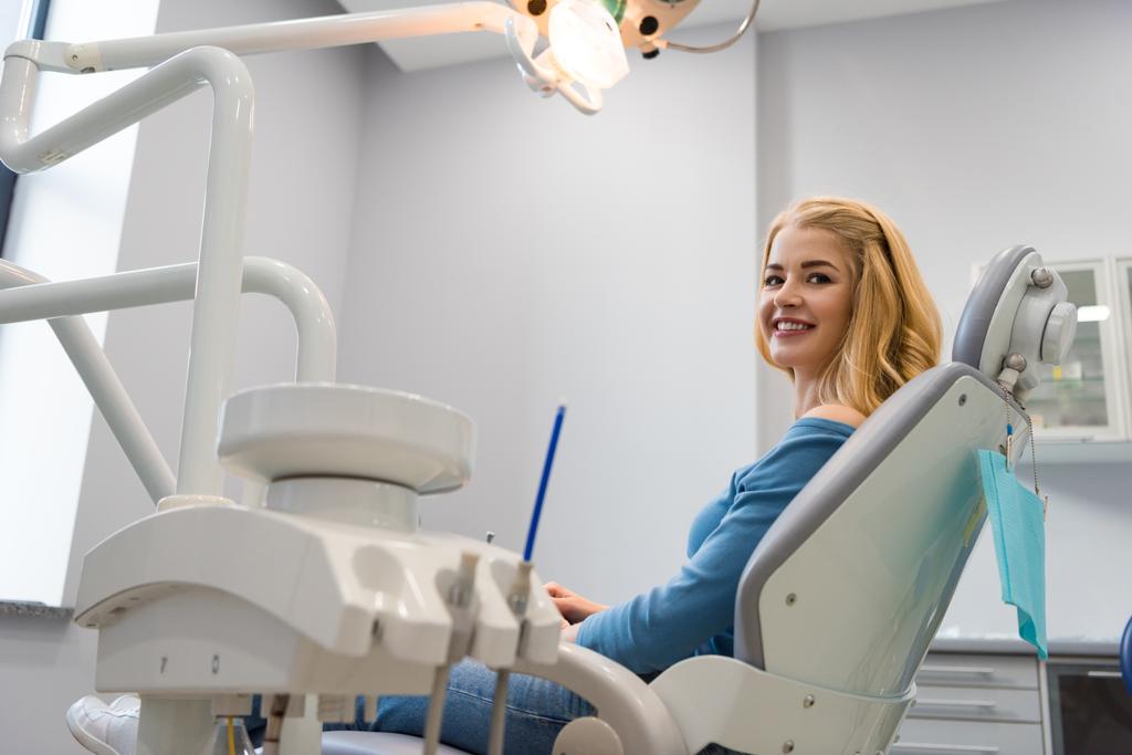 красивая молодая женщина, сидящая в стоматологическом кресле в кабинете дантиста
 - Фото, изображение