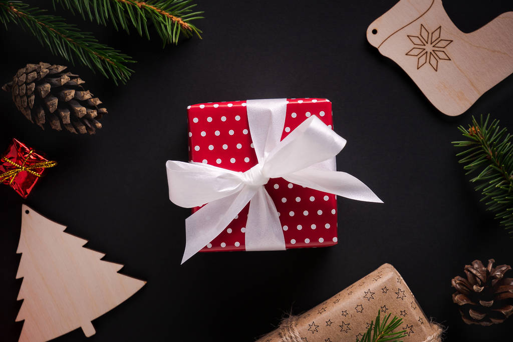 De gift van Kerstmis verpakt in rood papier met witte stippen en lint - Foto, afbeelding