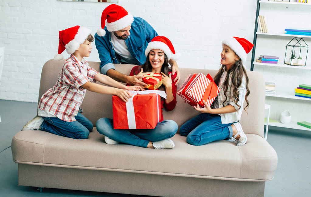 クリスマス プレゼント サンタ帽子で陽気な家族は、リビング ルーム - 写真・画像