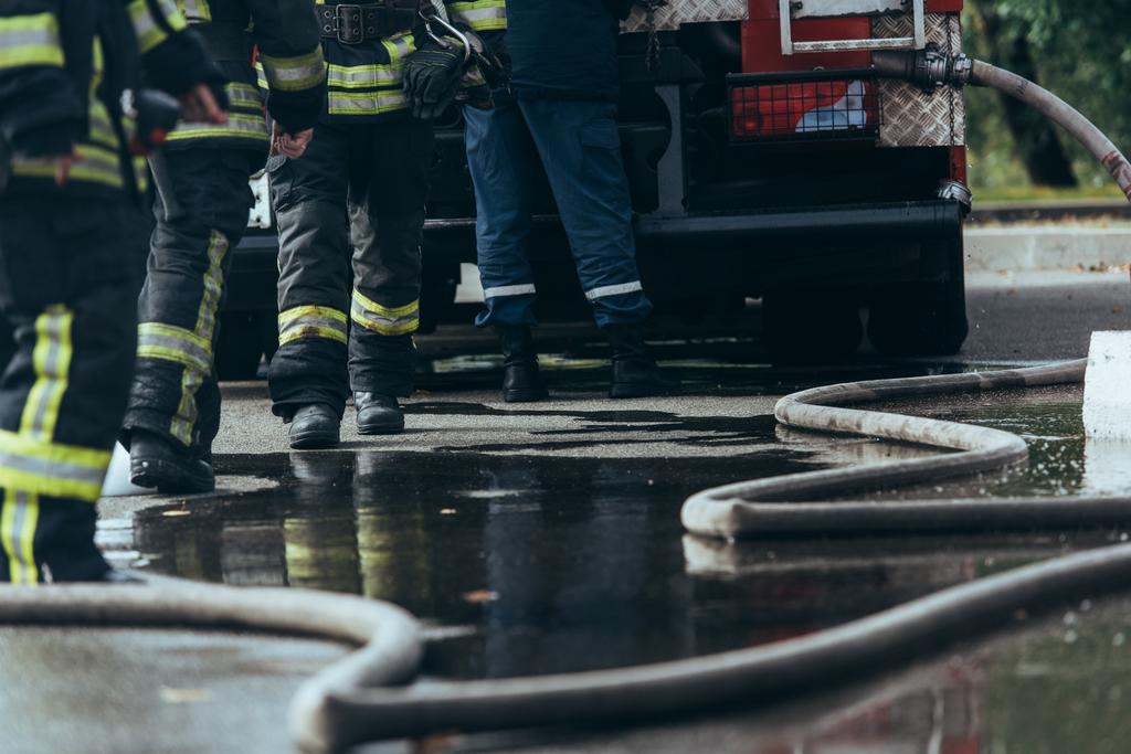 частичный обзор бригады пожарных и водяного шланга на земле на улице
 - Фото, изображение