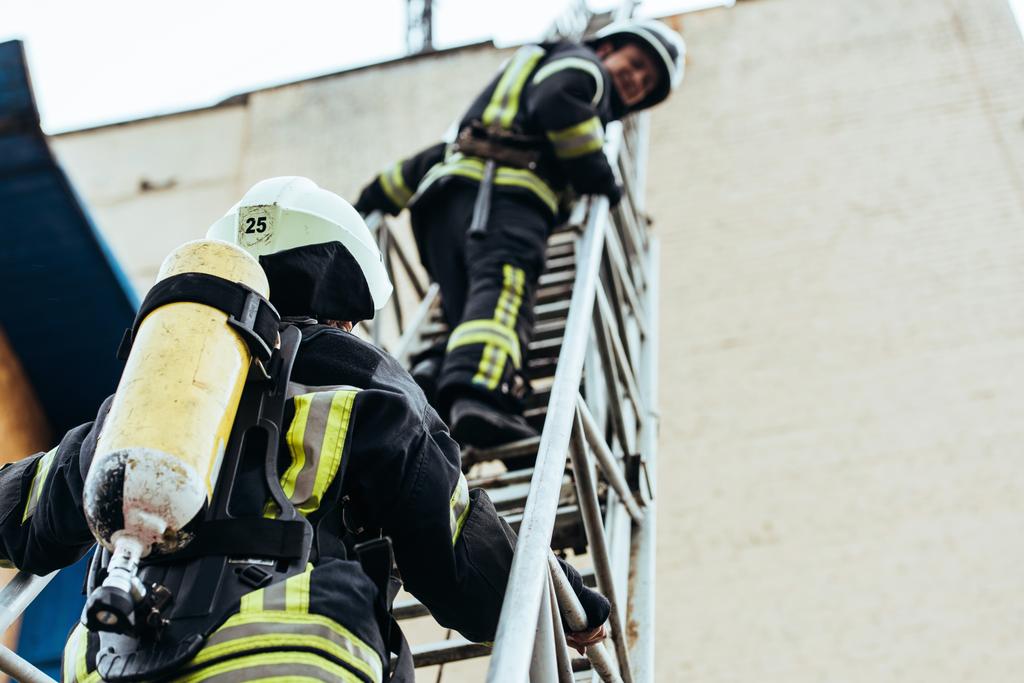 palomiesten valikoiva keskittyminen tulenkestävässä univormussa tikkailla
 - Valokuva, kuva