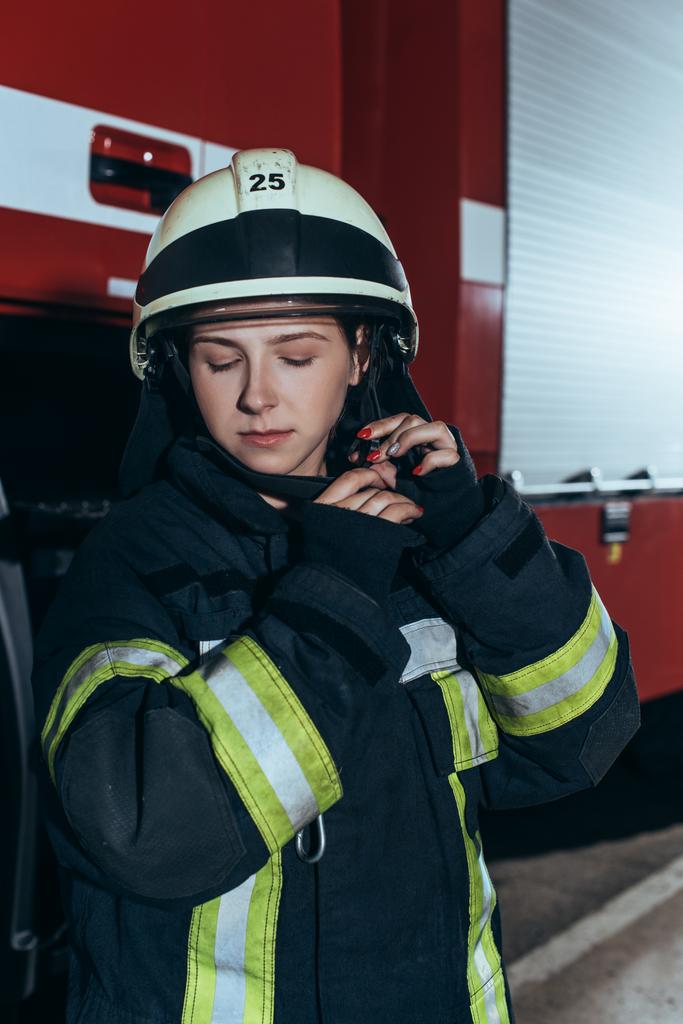 retrato de bombeira em uniforme verificando capacete no corpo de bombeiros
 - Foto, Imagem