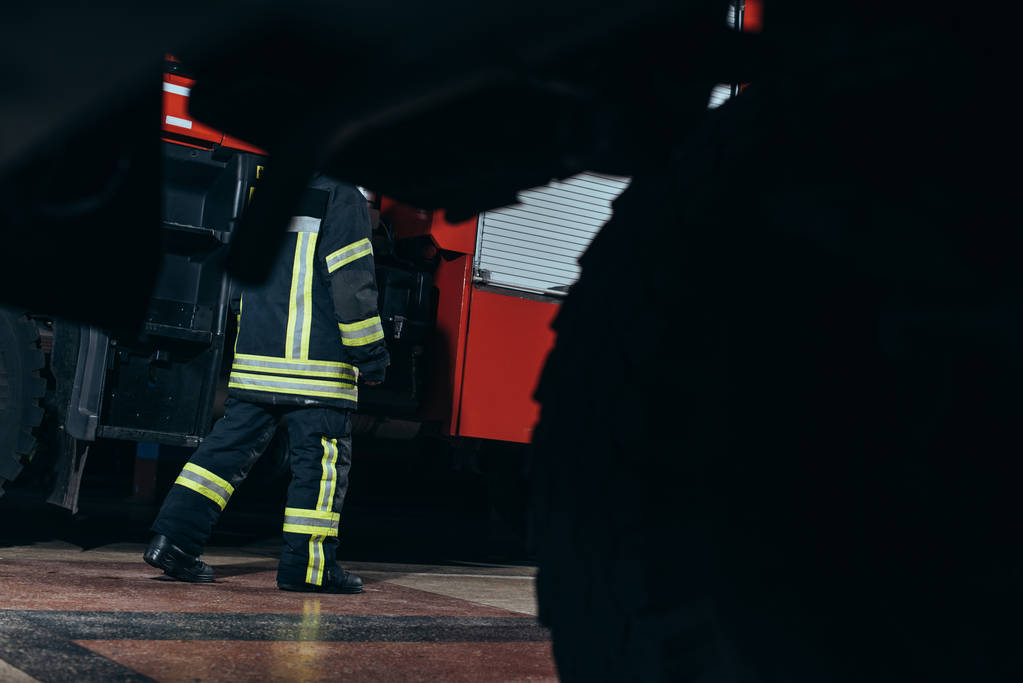 vista parcial del bombero en uniforme ignífugo protector caminando en la estación de bomberos
 - Foto, imagen