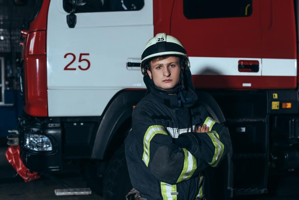 portrét hasič v ochranném jednotné a helmu s náručí překračovat na hasiče - Fotografie, Obrázek