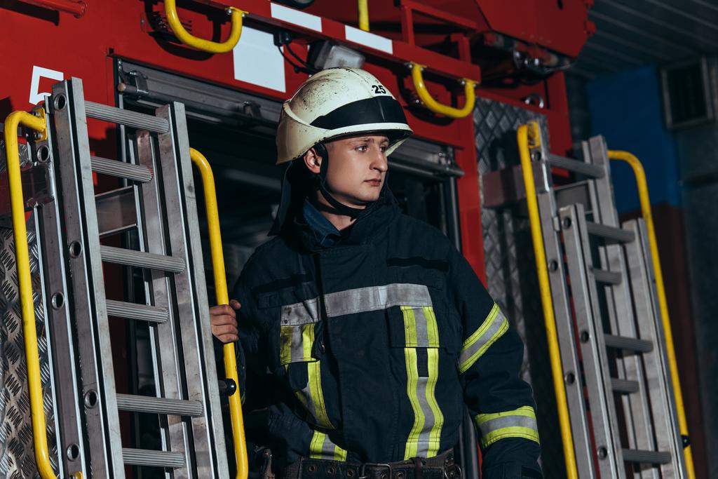 Yangın İstasyonu itfaiyeci koruyucu üniforma içinde ve uzak, kask - Fotoğraf, Görsel