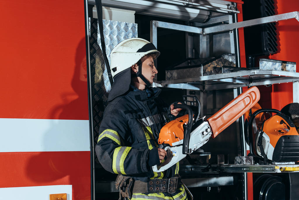 strażak w elektryczne gospodarstwa hełm zobaczył stojącą w samochodzie w straży pożarnej - Zdjęcie, obraz