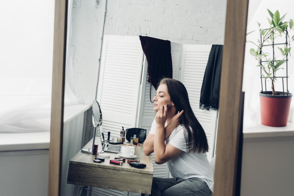 pohled přes zrcadlo odraz na mladé transgender žena dělá make-up doma - Fotografie, Obrázek