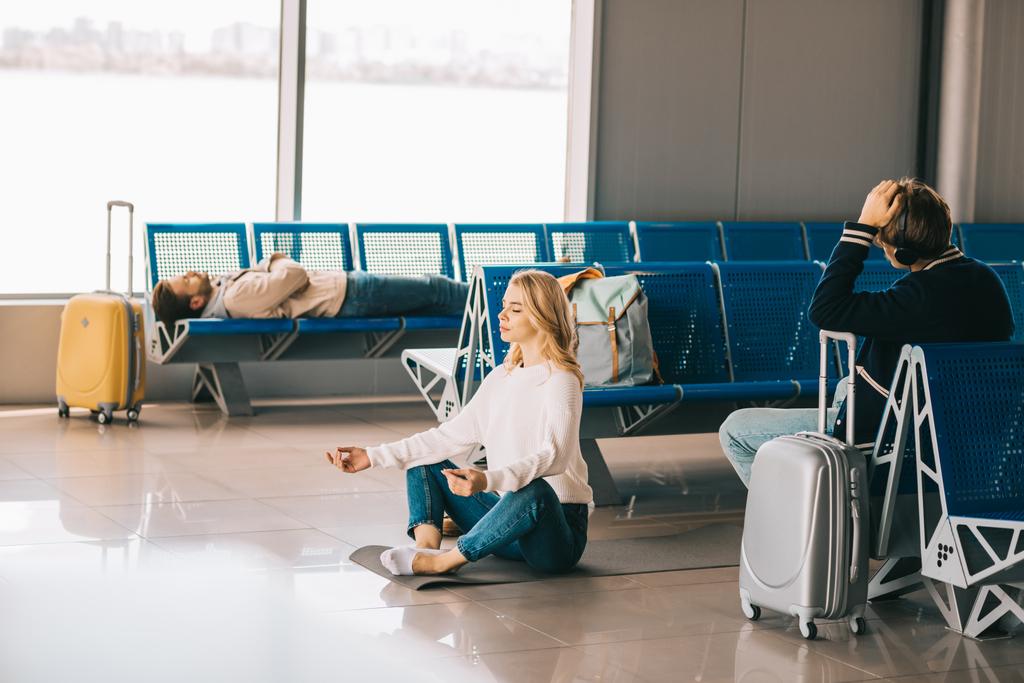 junge Frau meditiert in Lotusposition, während sie im Flughafenterminal auf ihren Flug wartet - Foto, Bild