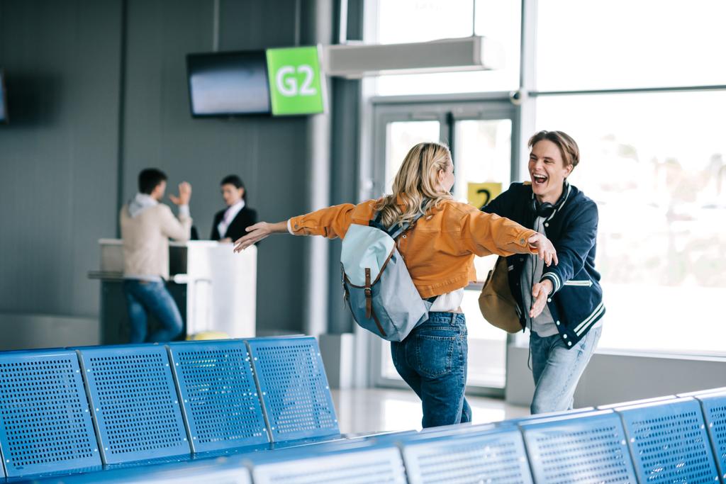 Havaalanı terminal sarılma sırt çantaları ile mutlu genç çift   - Fotoğraf, Görsel