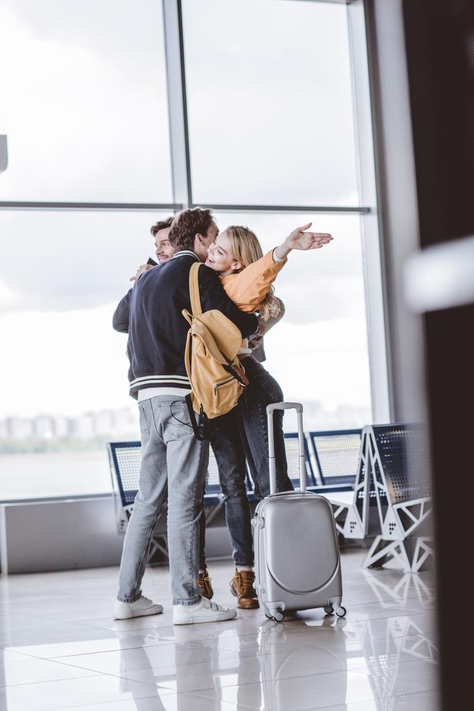 щасливі молоді друзі обіймають і вітають один одного в аеропорту
 - Фото, зображення