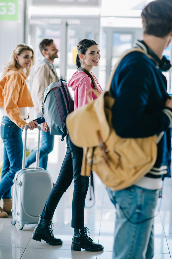 счастливые молодые люди с багажом в терминале аэропорта
 - Фото, изображение