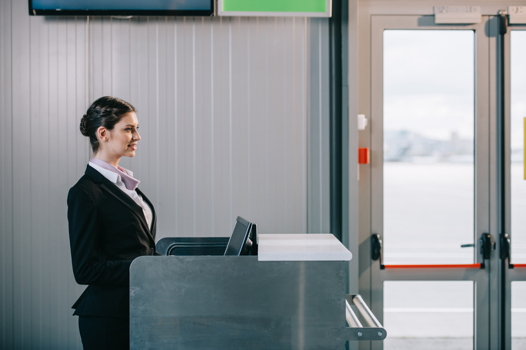 puolella näkymä kaunis nuori naispuolinen työntekijä lähtöselvitystiskillä lentokentällä
 - Valokuva, kuva