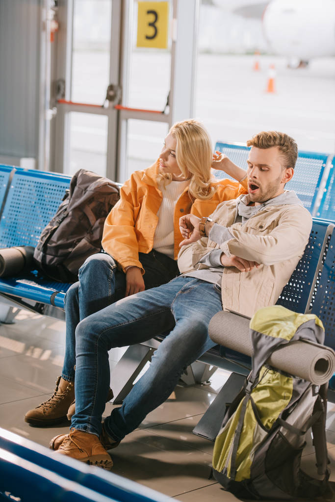 visão de alto ângulo de jovem casal entediado à espera de voo no aeroporto
  - Foto, Imagem