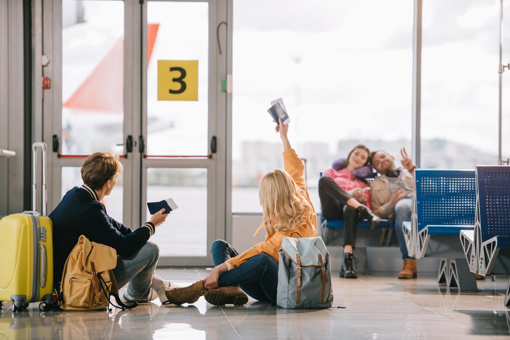 jóvenes viajeros con pasaportes y tarjetas de embarque saludándose en la terminal del aeropuerto
 - Foto, imagen