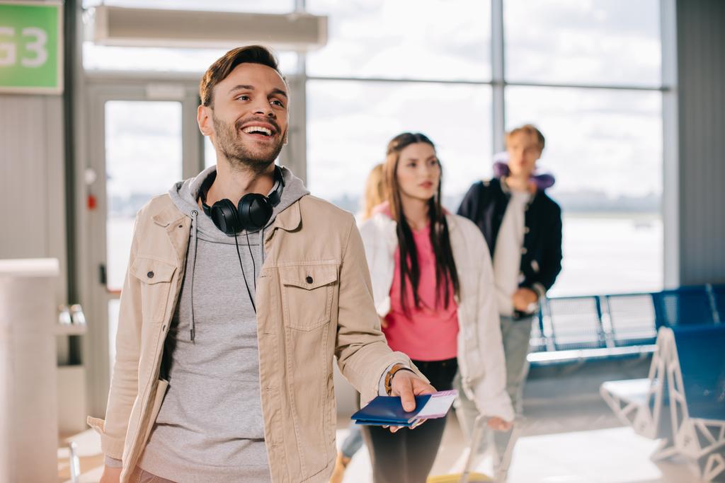 Genç adam holding pasaportlar gülümseyen ve havaalanı terminal geçişlerinde yatılı - Fotoğraf, Görsel