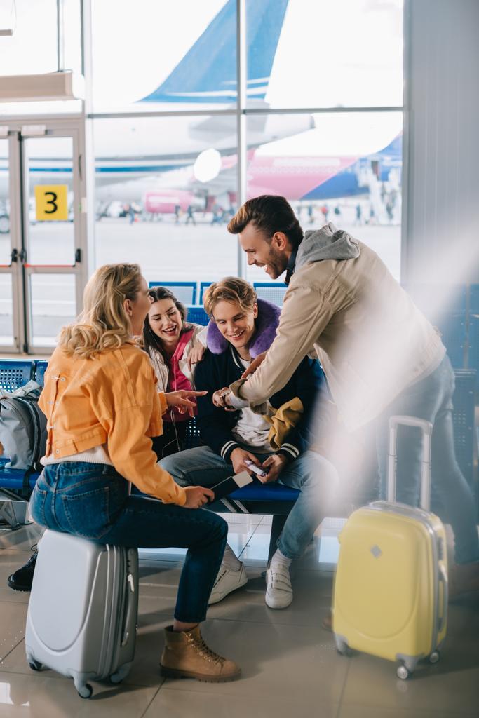 amigos registrando el tiempo mientras esperan con el equipaje en la terminal del aeropuerto
 - Foto, Imagen