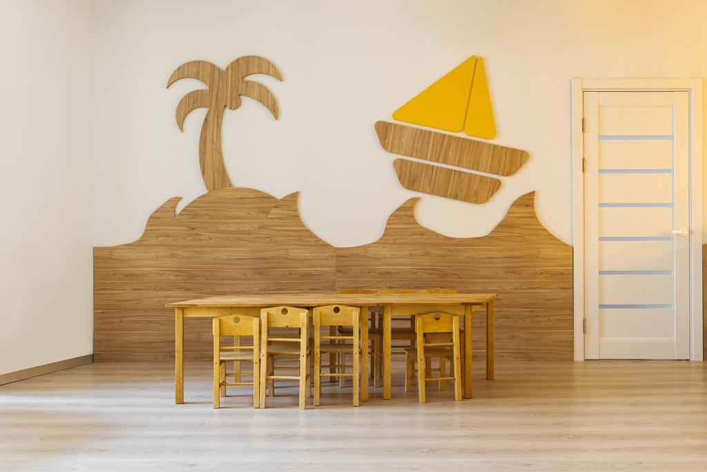 木製のテーブルと椅子、現代の幼稚園の壁に装飾的な要素と居心地の良い部屋 - 写真・画像