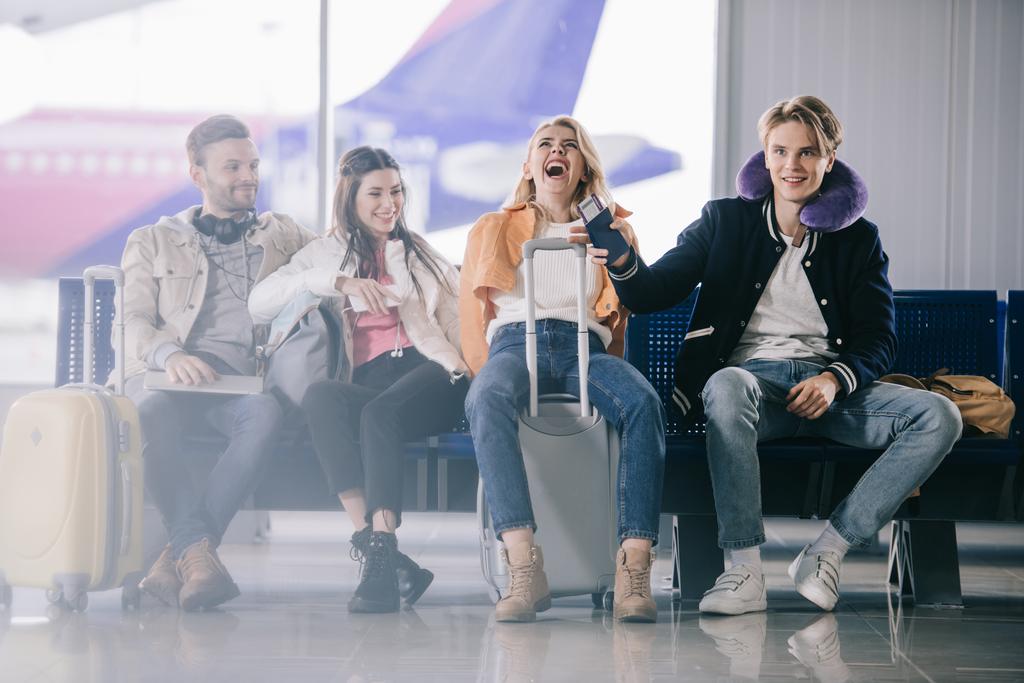 giovani che parlano e ridono mentre aspettano nel terminal dell'aeroporto
 - Foto, immagini