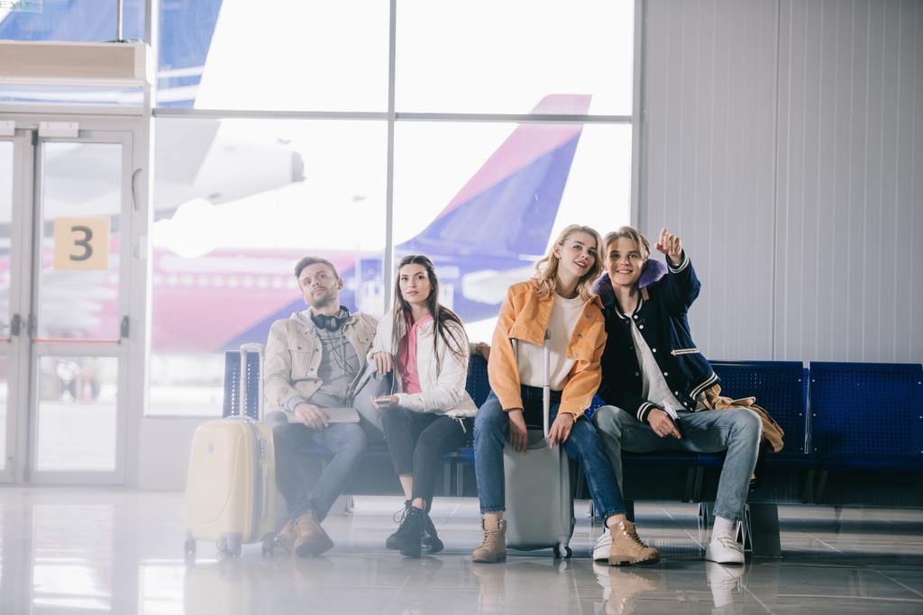 молодые друзья с багажом ждут в терминале аэропорта
   - Фото, изображение