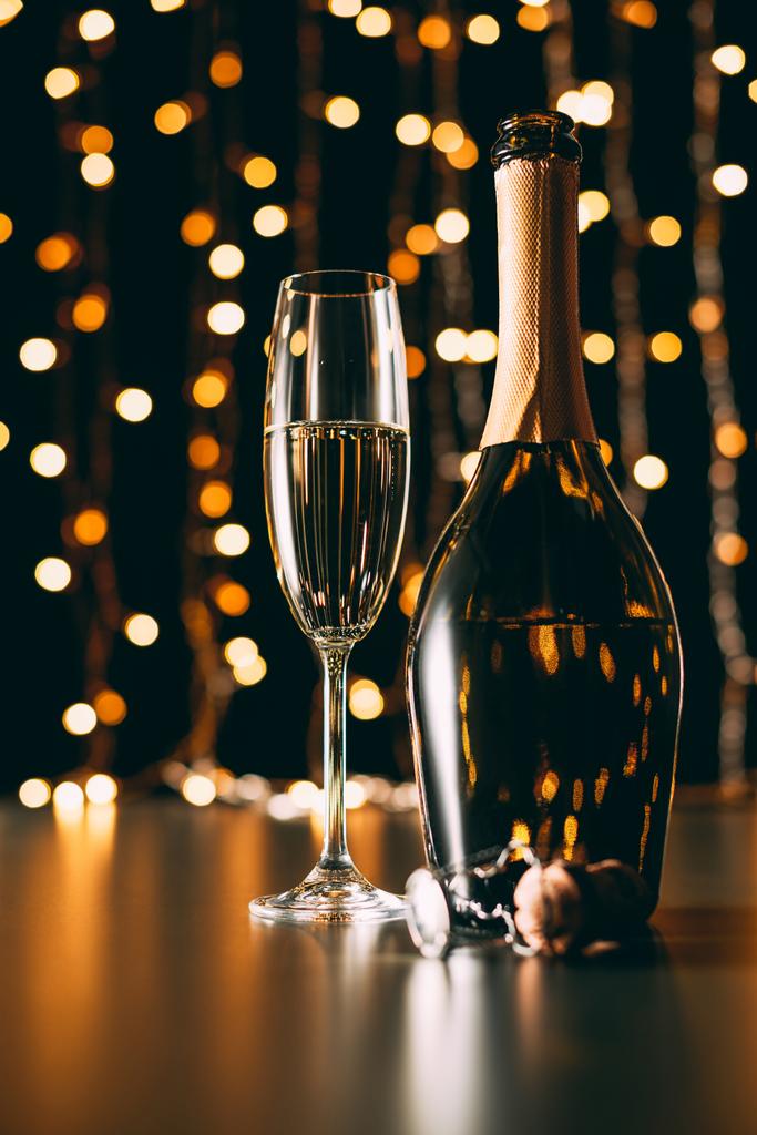 glass of champagne and bottle on garland light background, christmas concept - Photo, Image