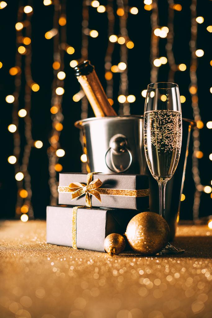 champagne in bucket and presents on garland light background, christmas concept - Photo, Image