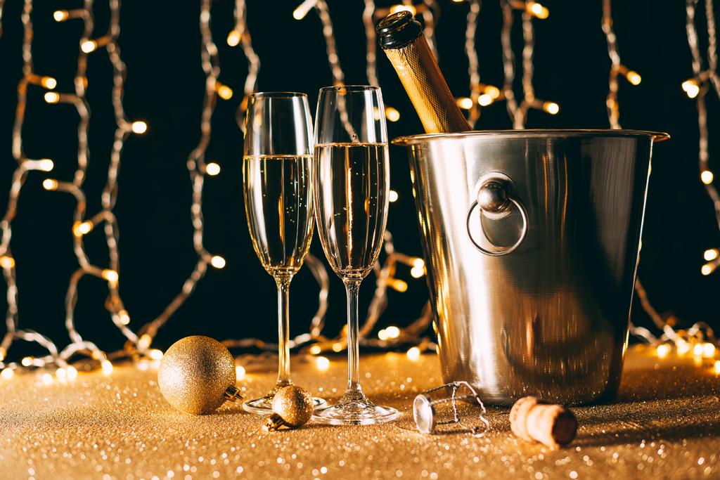 dos copas y botella de champán en cubo sobre fondo claro guirnalda, concepto de Navidad
 - Foto, Imagen