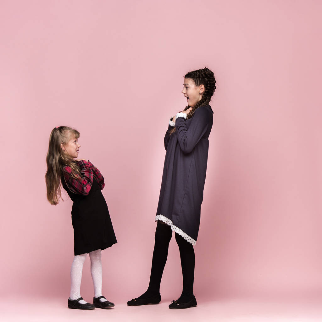 Enfants élégants mignons sur fond de studio rose. Les belles adolescentes debout ensemble
 - Photo, image