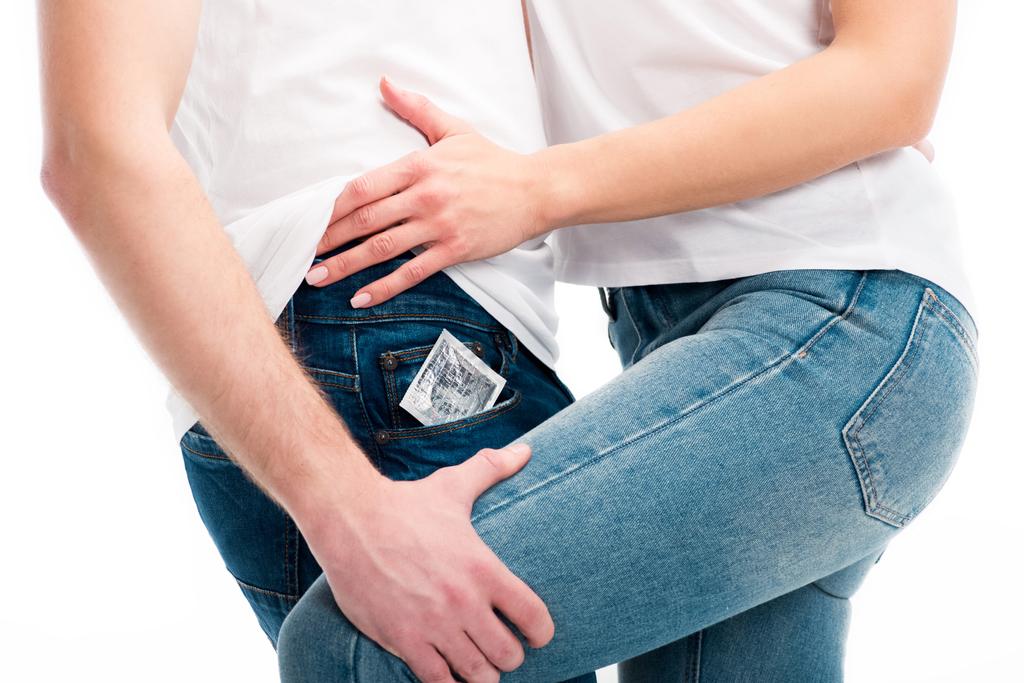 cropped image of heterosexual couple hugging, condom in pocket isolated on white, world aids day concept - Photo, Image
