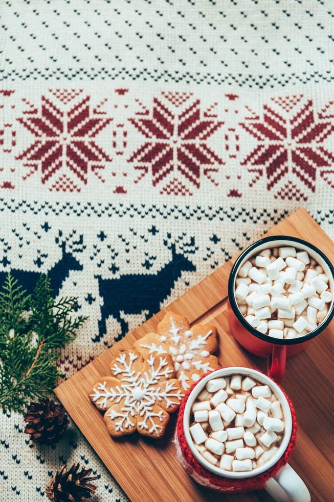 pohled shora šálků horké čokolády s marshmallows a soubory cookie na svetr pozadí, vánoční snídani koncept - Fotografie, Obrázek