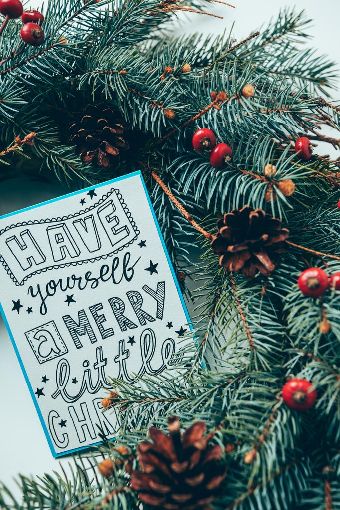 vista superior de las ramas de pino y la postal de invierno con tener usted mismo feliz letra de Navidad poco en la mesa blanca
 - Foto, imagen