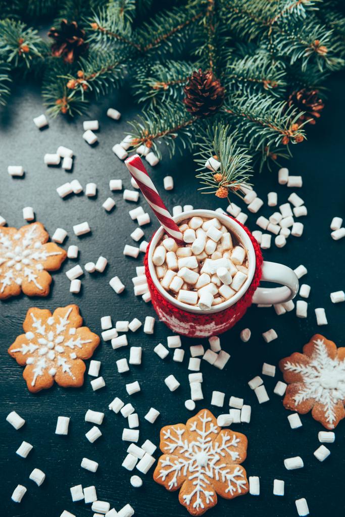 posa piatta con tazza di bevanda calda con marshmallow, biscotti e rami di pino su tavolo nero, Natale e Capodanno concetto di vacanze
 - Foto, immagini