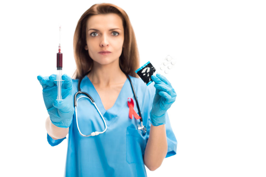 atractivo médico con cinta roja mostrando jeringa con sangre y condón con pastillas aisladas en blanco, el mundo ayuda concepto del día
 - Foto, Imagen