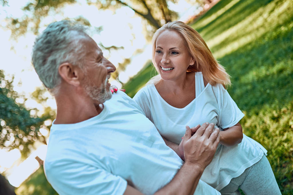 Старшая пара проводит время вместе на улице. Бородатый красивый мужчина и привлекательная женщина обнимаются, находясь в парке.
. - Фото, изображение