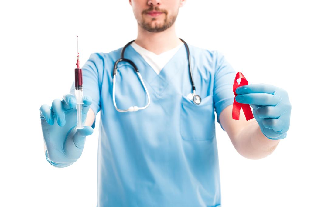 cropped image of doctor showing red ribbon and syringe with blood isolated on white, world aids day concept - Photo, Image