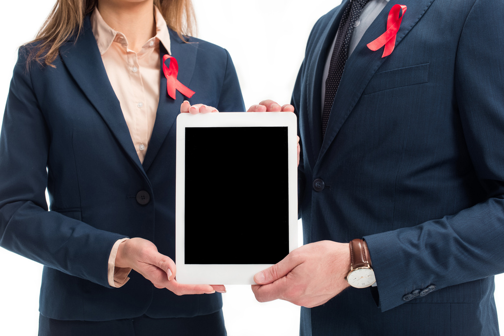 skadrowana biznesmeni z czerwonymi wstążkami na garnitury, trzymając tablet z pustego ekranu na białym tle, świat pomaga dzień koncepcji - Zdjęcie, obraz