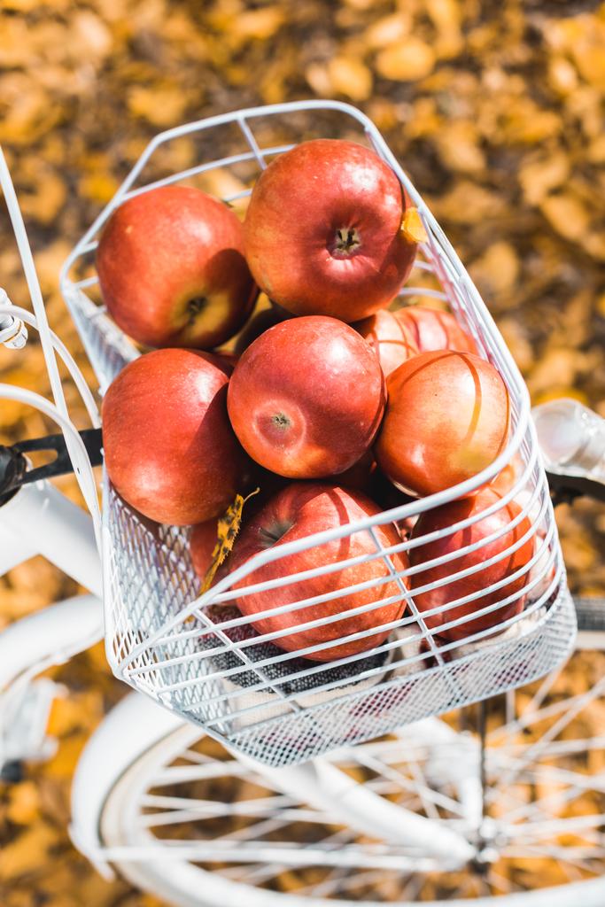 lähikuva polkupyörän kori täynnä herkullisia punaisia omenoita ulkona
  - Valokuva, kuva