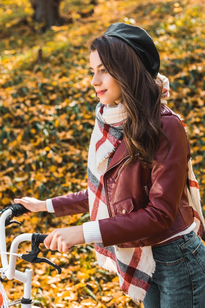 enfoque selectivo de la mujer alegre en la chaqueta de cuero elegante y la boina que lleva la bicicleta al aire libre
  - Foto, imagen