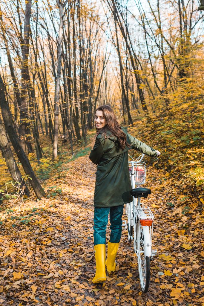 mulher atraente alegre carregando bicicleta na floresta outonal amarela
  - Foto, Imagem